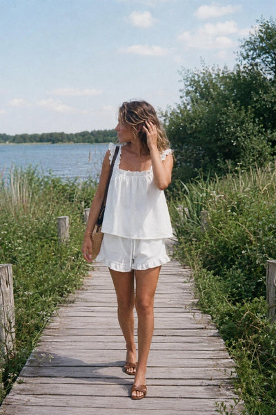 White ruffled summer set on a wooden jetty by a lake