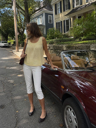 Yellow top with white capri trousers next to a vintage convertible